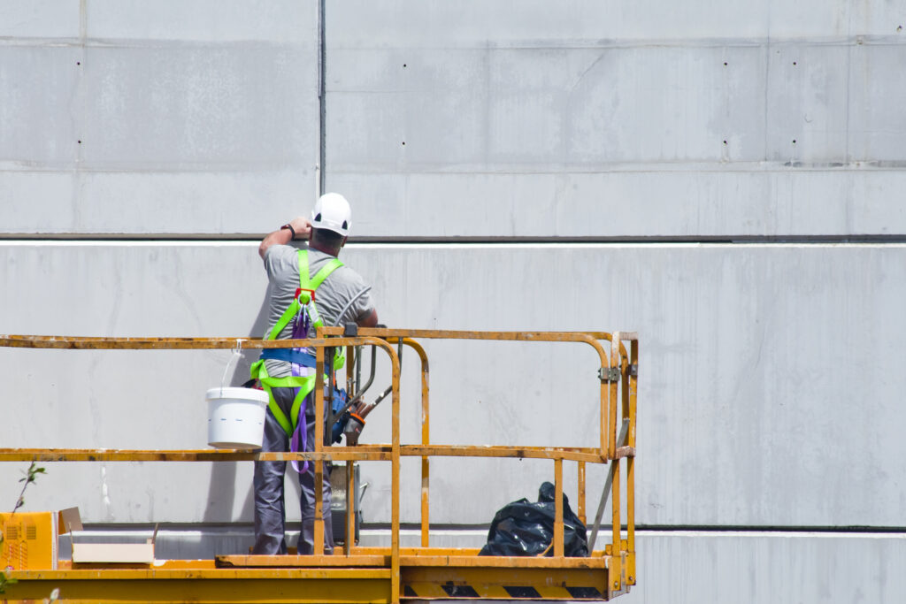 facaderenovering Køge - Maler på stillads i gang med facaderenovering